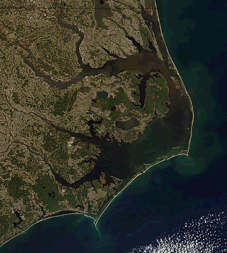 The Outer Banks (frequently abbreviated OBX) are a 200 mi (320 km) string of barrier islands and spits off the coast of North Carolina and southeastern Virginia, on the east coast of the United States. They line most of the North Carolina coastline, separating Currituck Sound, Albemarle Sound, and Pamlico Sound from the Atlantic Ocean. A major tourist destination, the Outer Banks are known for their wide expanse of open beachfront and the Cape Hatteras National Seashore. The seashore and surrounding ecosystem are important biodiversity zones, including beach grasses and shrubland that help maintain the form of the land.
The Outer Banks were sites of early European settlement in the United States and remain important economic and cultural sites. Most notably the English Roanoke Colony vanished from Roanoke Island in 1587 and was the first location where an English person, Virginia Dare, was born in the Americas. The hundreds of shipwrecks along the Outer Banks have given the surrounding seas the nickname Graveyard of the Atlantic. The Outer Banks were also home to the Wright brothers' first flight in a controlled, powered, heavier-than-air vehicle on December 17, 1903, at Kill Devil Hills. During the 20th century the region became increasingly important for coastal tourism.
The Outer Banks are particularly vulnerable to sea level rise and coastal erosion; the effects of climate change compounds existing coastal erosion caused by poor coastal management and construction practices. In some locations on the banks, sea levels rose 5 inches from 2011 to 2015. Some sections have significantly eroded already, with portions of Hatteras Island at 25% of its original width as of 2014. Tropical storms like Hurricane Irene in 2011 have already destroyed significant infrastructure and property.

